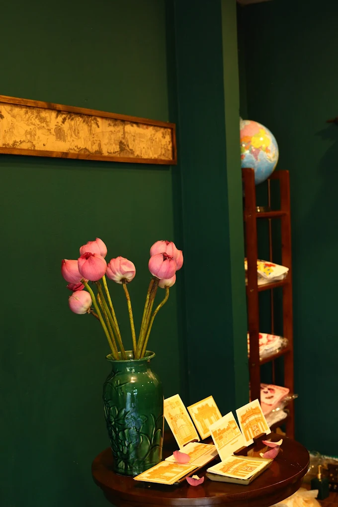 A vase of pink flowers beside art souvenirs in an emerald corner